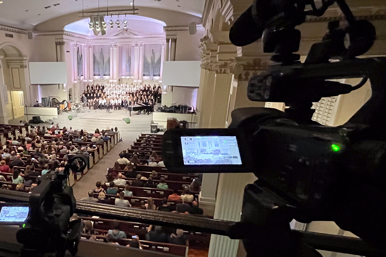 An image of a camera filming a concert in a large church.